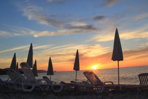 eine Gruppe von Stühlen und Sonnenschirmen am Strand mit Sonnenuntergang in der Unterkunft Hotel Za Maria in Santo Stefano di Camastra