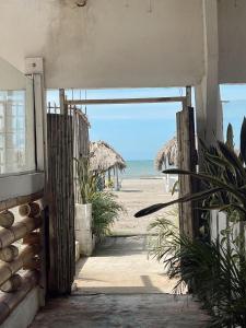une porte ouverte donnant sur une plage avec des parasols en paille dans l'établissement El legado de las olas, à Carthagène des Indes