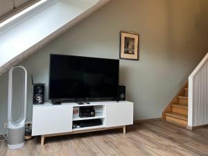 TV de pantalla plana en un centro de entretenimiento blanco en Chez Fernand, en Hotton