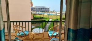einen Balkon mit Stühlen und einem Tisch sowie Poolblick in der Unterkunft Modern Front Seaview chalet El Sokhna in Ain Suchna