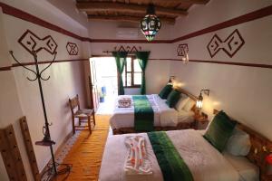 a bedroom with two beds and a lamp at Maison d'Hôte Argana in Aït Idaïr
