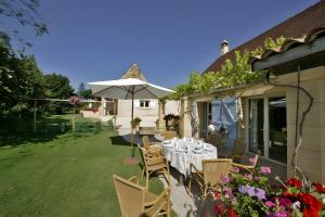 a table with chairs and an umbrella on a patio at Gite Four De Mon Père in Salignac Eyvigues