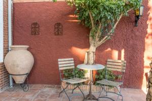 Ein Tisch, zwei Stühle und eine Vase stehen neben einer Wand. in der Unterkunft Ferienhaus für 4 Personen und 2 Kinder in Durcal, Andalusien Provinz Granada in Dúrcal