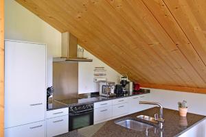 cocina con encimeras blancas y techo de madera en Chesa Filomela, en Bever 7 fotos más