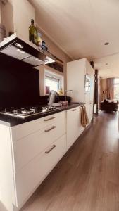 Una cocina con gabinetes blancos y un refrigerador blanco. en 't Haasnestje, en Harderwijk 44 fotos más