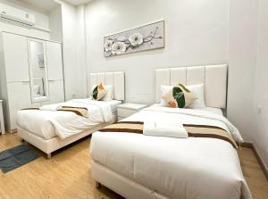 two beds in a room with white walls at Pearl Homestay Hat Yai in Hat Yai