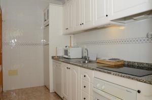 eine Küche mit weißen Schränken und einer Spüle in der Unterkunft Ferienhaus für 6 Personen ca 88 m in Estrella de Mar, Murcia Costa Calida in Los Urrutias + 32 Fotos