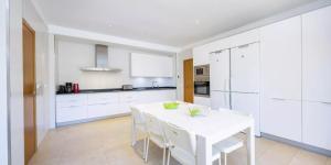 una cucina bianca con tavolo bianco e armadi bianchi di Son Ropit a Calas de Mallorca