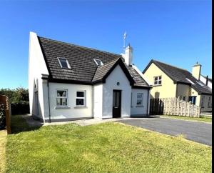 a white house with a black roof at Beautiful Spacious 4-Bedroom House in Louisburgh in Louisburgh