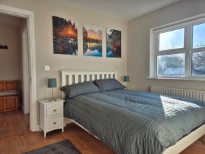 a bedroom with a bed and three paintings on the wall at Beautiful Spacious 4-Bedroom House in Louisburgh in Louisburgh