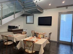 comedor con 2 mesas y TV de pantalla plana en Sweet Dreams Residence, en Brugine