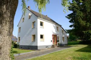 a white house with a tree in front of it at Ruhiges Ferienhaus In Lommersdorf Mit Garten in Blankenheim