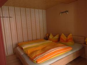 a bedroom with a bed with orange and yellow pillows at Wohnung In Ilfeld Mit Grill Und Garten in Harztor