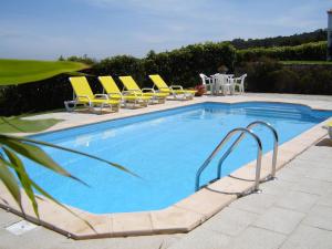 a swimming pool with yellow lounge chairs and a table at Casa Do Moinho in Colares