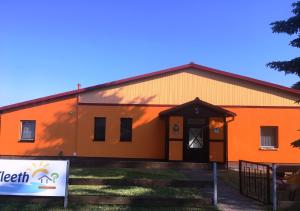 ein großes orangefarbenes Gebäude mit einem Schild davor in der Unterkunft Ferienwohnung für 6 Personen  1 Kind ca 85 m in Fleeth, Mecklenburg-Vorpommern Mecklenburgische Seenplatte in Mirow