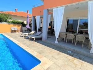 a villa with a swimming pool and a dining area at Villa Summer Escape In Barbat Mit Garten Und Aussicht in Barbat na Rabu