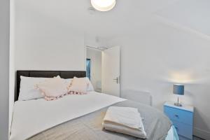 um quarto branco com uma cama grande com almofadas rosa em 6 Rushbrooke Hotel Apartments Cobh County Cork em Cobh