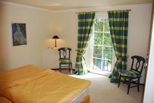 ein Schlafzimmer mit einem Bett und zwei Stühlen und einem Fenster in der Unterkunft Ferienwohnung für 3 Personen ca 70 m in Swantow, Ostseeküste Deutschland Rügen in Poseritz