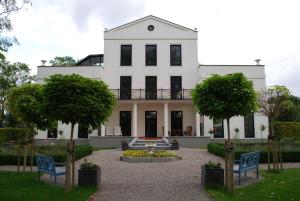 ein großes weißes Haus mit zwei Bäumen im Hof in der Unterkunft Ferienwohnung für 3 Personen ca 70 m in Swantow, Ostseeküste Deutschland Rügen in Poseritz