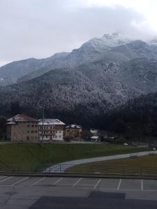 ein Parkplatz mit einem Gebäude und Bergen im Hintergrund in der Unterkunft Dolomiti Apartment in Domegge di Cadore
