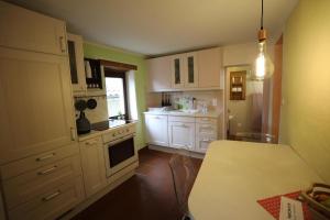 une cuisine avec des armoires blanches et une table à l'intérieur dans l'établissement Casa Holamundo, à Curtina