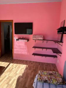 Cette chambre est dotée d'un mur rose et d'une télévision à écran plat. dans l'établissement Casa na beira do rio com Lareira, à Itati