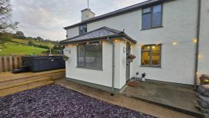 Casa blanca con porche y patio en Cwm Uchaf Holiday Home, hot tub and horse view!, en Abergele