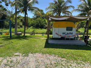 une caravane jaune et blanche avec un gazebo dans l'établissement Rancho Duas Luas Apoio Camping, à Rio das Ostras