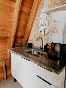 een keuken met een spoelbak en een aanrechtblad bij Chalé Tia Barbara in Itutinga