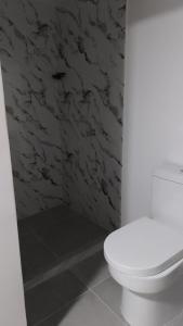 a bathroom with a white toilet and a stone wall at Hotel coral Issa in Bahía Solano +14 photos