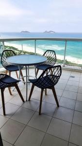 a table and chairs on a balcony with the beach at VISTA ESPETACULAR - TWIN TOWERS - Barra da Tijuca in Rio de Janeiro