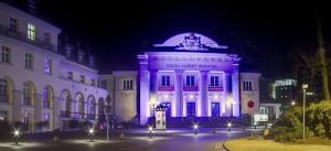 ein Gebäude, das nachts lila beleuchtet ist in der Unterkunft Ferienwohnung in Bad Elster mit Grill, Terrasse und Garten in Bad Elster + 4 Fotos