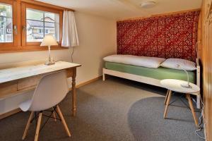 Habitación pequeña con cama, escritorio y escritorio. en Haus Zum Reh, en Krummenau