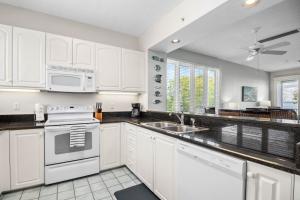 a kitchen with white cabinets and a sink and a microwave at Cedars East #822 in Longboat Key
