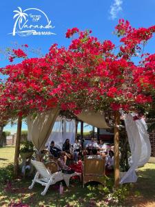 a group of people sitting under a gazebo with red flowers at Espaço Varanda e Mar in São Miguel do Gostoso