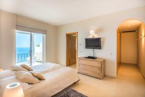 a bedroom with a large bed and a television at Villa La Terrasse by HR Madeira in São Gonçalo