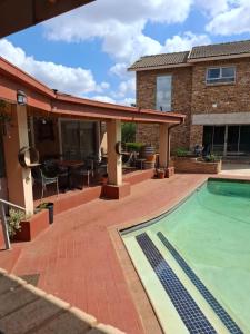 Casablanca Guesthouse في Carletonville: فناء به مسبح و منزل