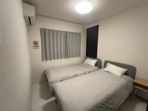 two beds in a small room with a window at 花園之家 in Osaka