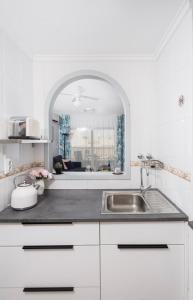 a white kitchen with a sink and a mirror at Rinconcito de Catalina in Torrevieja