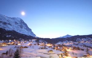 a town in the snow at night with mountains at Chalet Gletscherfloh in Grindelwald