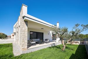 Cette maison blanche dispose d'une terrasse avec un arbre. dans l'établissement Villa Dolcea Elegant Und Stilvoll Mit Pool, à Kaštel