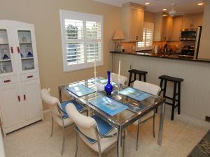 una sala da pranzo con un tavolo di vetro e sedie bianche di Whitney Beach #142 a Whitney Beach