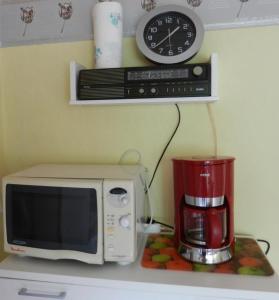 un micro-ondes posé sur un comptoir avec une cafetière et une horloge dans l'établissement Ferienwohnung Preiser In Schieder Schwalenberg, à Schieder-Schwalenberg