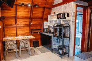 a kitchen with wooden walls and a table and a microwave at Chalé Nosso Kadito - Glamping Estrada Real in Itutinga