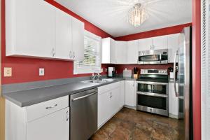 a kitchen with white cabinets and a red wall at Beach Breeze West in Bradenton Beach