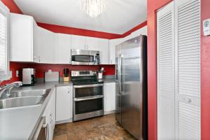 a kitchen with a stainless steel refrigerator and red walls at Beach Breeze West in Bradenton Beach +25 photos