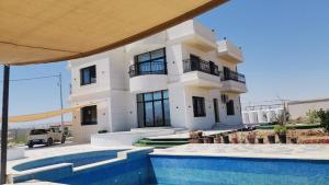 a white house with a swimming pool in front of it at Rest Sea Chaliet & Farm in Edh Dhrā‘