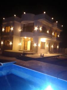 ein großes Haus bei Nacht mit einem Swimmingpool in der Unterkunft Rest Sea Chaliet & Farm 