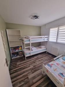 a bedroom with two bunk beds and wooden floors at Sainte Cécile: appartement 2ch 6/7 pers in Camiers