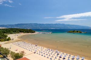 ein Strand mit Stühlen und Sonnenschirmen und das Meer in der Unterkunft Apartments BePa in Lopar